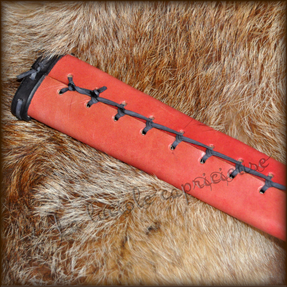 Vue détaillée de l'arrière d'un fourreau d'épée médiévale, tressage noir sur fond rouge