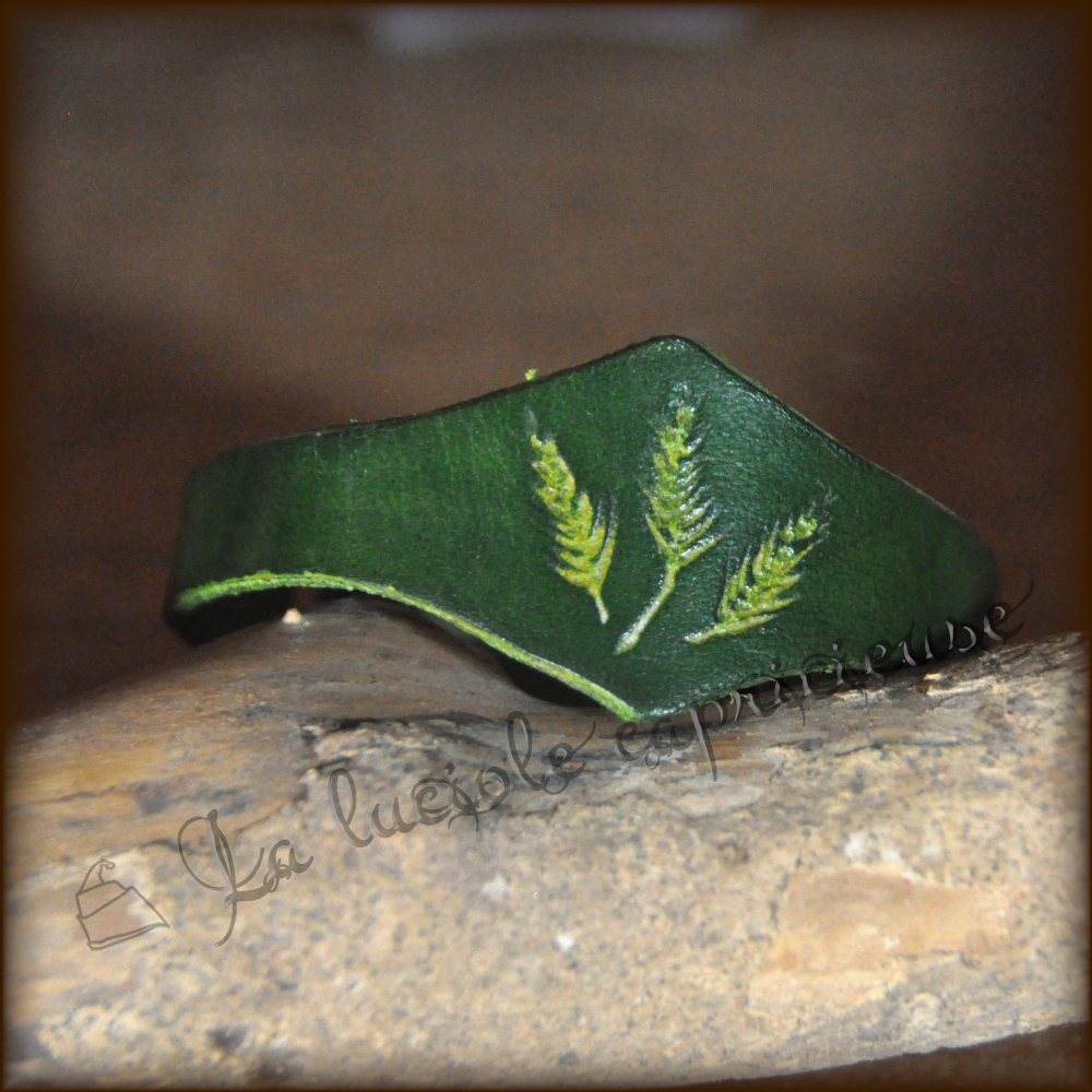 Vue détaillée d'un bracelet fait main en cuir de bovin tanné végétal, empreinte végétale, teinté vert