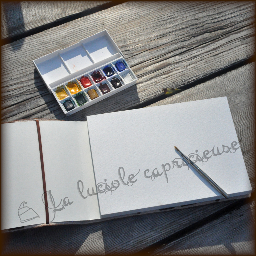 Intérieur d'un bloc aquarelle avec couverture en cuir, peinture et pinceaux