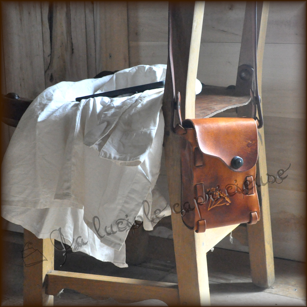 Petite sacoche en cuir marron, faite main sans coutures, posée sur un dossier de chaise